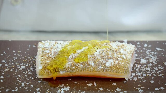 The cook prepares zander, pikeperch fillet. The chef pours olive oil on the raw white fish fillet. Slow motion video 100fps