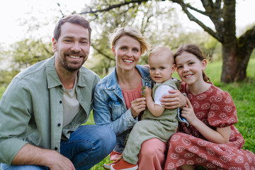 Family portrait with daughter and small toddler, baby, outdoors in spring nature.