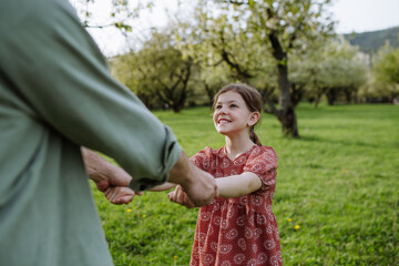 Father spinning daughter around, holding her hands. Dad and girl having fun, laughing outdoor. Father's day concept.