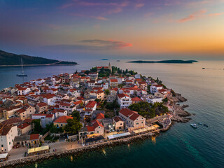 Primosten, Croatia - Aerial view of Primosten peninsula and old town on a sunny summer morning in Dalmatia, Croatia. Blue and golden sky at sunrise on the Adriatic sea coast