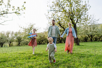 Family portrait with daughter and small toddler, baby, walking outdoors in spring nature.
