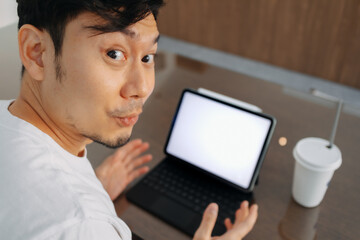Asian man wow and amazed face, hand presenting white blank screen of laptop, got some idea, great choice, working and sitting in cafe.