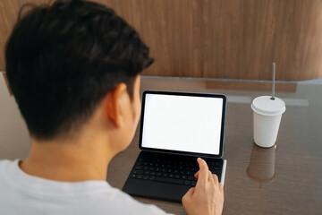 Back view of man using laptop, hand typing keyboard showing white blank screen, a cup of coffee putting on table. freelance concept. 