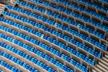Blue and white stadium seats arrayed in a diagonal pattern, showcasing a visually striking contrast and structure in an empty stadium.