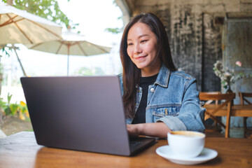 Portrait image of a young woman working on laptop computer in cafe
