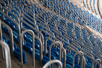 Sea of blue stadium seats captured in empty sports arena, emphasizing the repetitive patterns and the quiet before storm of activity.