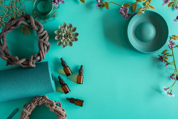Tranquil Spa Setting with Yoga Mat, Essential Oils, and Decorative Flowers on Turquoise Background