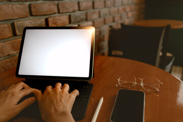 Back side view of asian woman using laptop, hand typing keyboard, showing white blank screen notebook, working as freelance in cafe alone. 