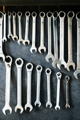 Combination wrenches set in auto repair shop. Mechanics repairing, maintaining car in garage.