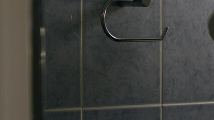 Hand changing toilet roll in bathroom 