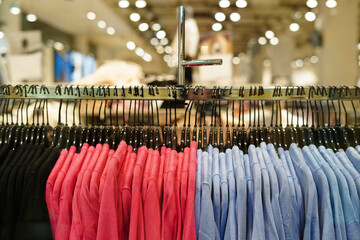 Clothes in pink and blue colors on hangers in a retail shop. Fashion and shopping center