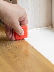 master of interior decoration, smears the joint of the tile and the kitchen countertop with white silicone instead of the skirting board, close-up