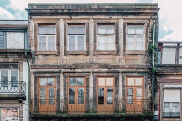 Facade of an abandoned residential building with broken and peeling windows located in the city of...