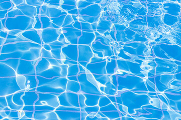 Blue swimming pool water surface and ripple wave background. Summer abstract reflection caustics in swimming pool.