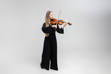 Full length portrait of attractive woman musician playing violin © zinkevych