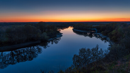 beautiful spring landscape, panoramic view of river and forest from above the hill, bright sunny day turns into sunset and dusk, sunlight reflects from water, river bank and flow of water