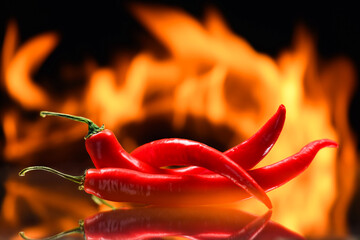 red chili peppers, on a background of burning fire, flames on a black background, hot and spicy spices