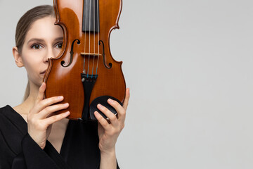 Young woman hiding her face with violin