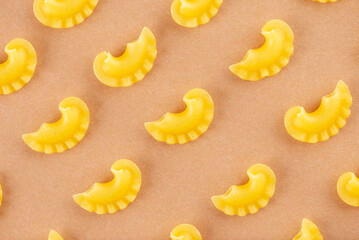 Pattern dry Italian pasta Creste Di Gallo on a beige background. Rooster scallop. Top view.
