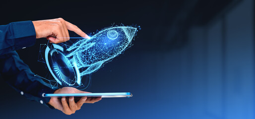 A hand interacts with a holographic projection of a rocket above a tablet, symbolizing startup...