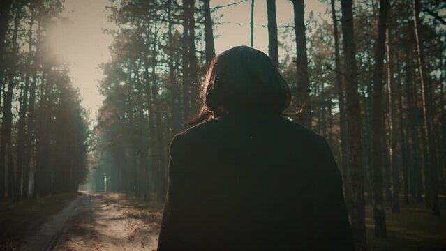 Serial killer with axe in woods wearing coat and wig for being unrecognizable, murderer searching for new victims in dark forest, man with axe over his shoulder. Bloodthirsty criminal maniac carrying