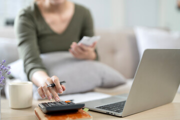 Close up of woman using calculator paying bills online, calculating household finances or taxes on...
