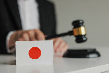 Judge's hand holding gavel. Flag of Japan. Concept of Japanese justice system