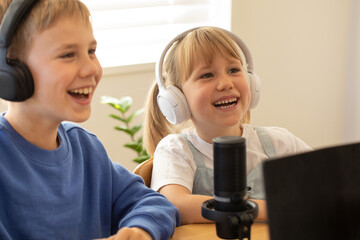 Joyful siblings sharing a laugh while recording a podcast at home. Blogging