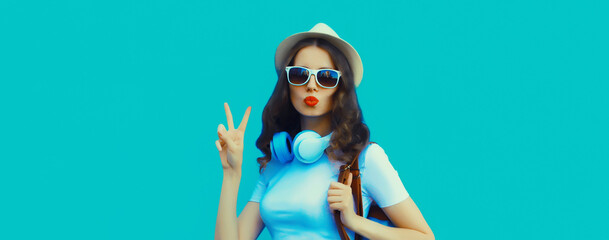 Happy modern happy young woman listening to music with headphones on blue background
