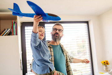 Playing with lightweight styrofoam planes. Playful father and son throwing and flying foam glider...