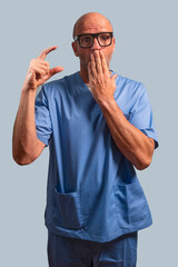 Portrait of a physiotherapist in a light blue coat and with his fingers indicating that he is tiny.