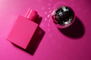 Rose perfume with disco ball on pink background, modern cosmetic, trendy spray, bright essence