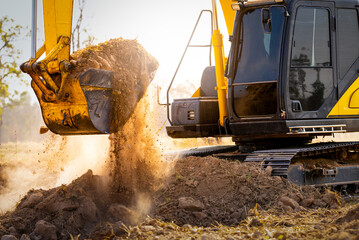 Obraz premium Close-up of excavator at construction site. Backhoe digging soil for earthwork and construction business. Excavating machine at work. Heavy machinery for earth moving and construction site development