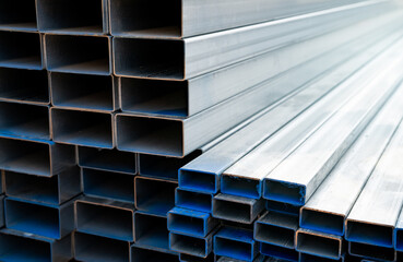Industrial warehouse stock of rectangular metal pipes for building and construction supplies. Stack of steel pipes. Iron materials for construction and infrastructure projects. Steel tubing storage.