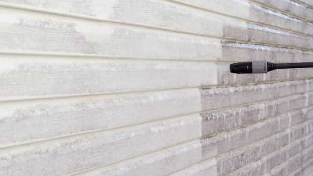 Power washing dirty vinyl siding. Close-up