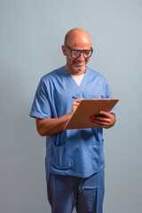 Portrait of a physiotherapist in light blue gown and holding a wooden folder.