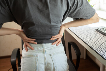 Back pain in a teenager, sedentary lifestyle, student hunched over desk, studying for hours, feeling discomfort.