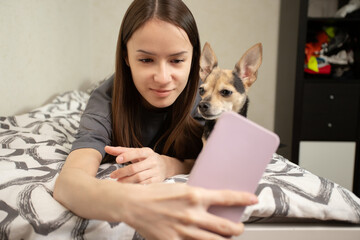 teenage student taking selfie photo with cute dog at home