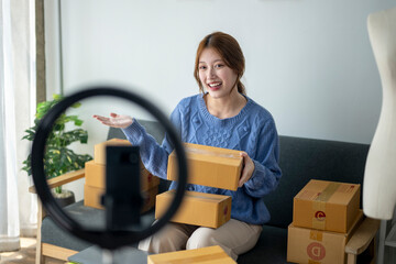 A woman is sitting on a couch holding a stack of boxes. She is smiling and she is happy. The scene...