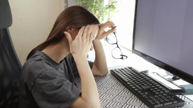 Teenager has headache, stressed at workplace, staring at computer screen.