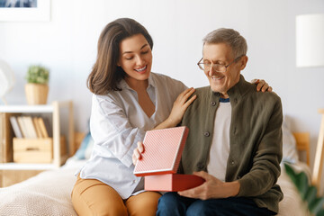 woman congratulating father and giving  him a gift