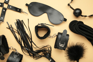 Set of erotic toys for BDSM on beige background. The game of sexual slavery with a whip, gag and leather blindfold. Intimate sex games. Space for text