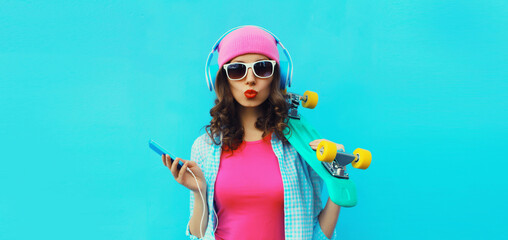 Stylish modern happy young woman listening to music in headphones with phone, colorful clothes