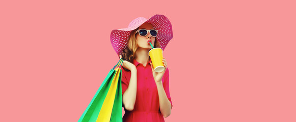 Portrait of beautiful young woman model with colorful shopping bags drinking juice in summer hat