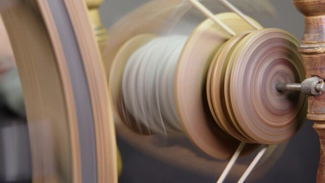 Full frame close-up: Traditional spinning wheel spindle spinning yarn