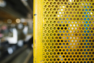 A Galvanised perforated metal sheet painted yellow. industrial machinery metal texture background,...