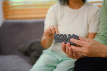Elderly couple putting pills into pill organizer. Health care, medicine and treatment concept