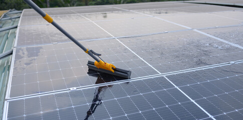 Close-up of the cleaning stick of a worker cleaning a solar panel.