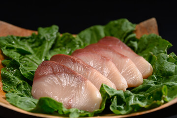Fresh raw Hamachi sashimi or yellowtail fish served on wooden plate. Traditional Japanese food