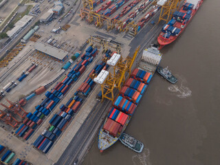 Aerial top view over international containers cargo ship at industrial import-export port prepare to load containers with big container loader ship vessel. global transportation and logistic business.